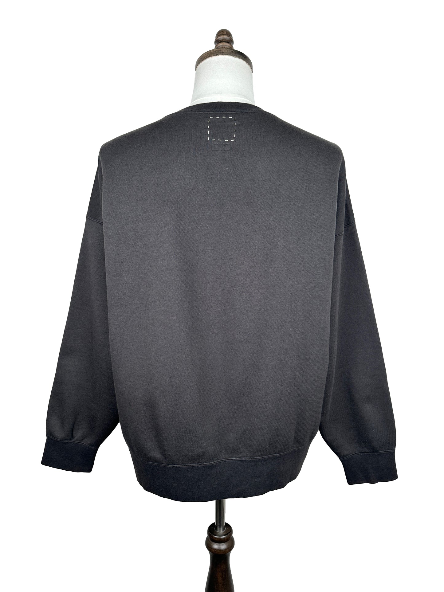 The Visvim FW23 Ultimate Jumbo SB Sweat L/S in black, shown from the back on a dress form, features an oversized fit and a stitched square detail near the upper center neckline.