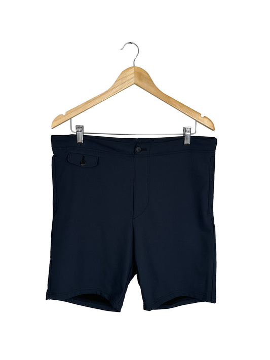 A pair of black SS21 VS Walker Slack Shorts (NY/SF) by Visvim, crafted from a nylon-wool blend, hangs on a wooden hanger and features a small flap pocket on the front left side.